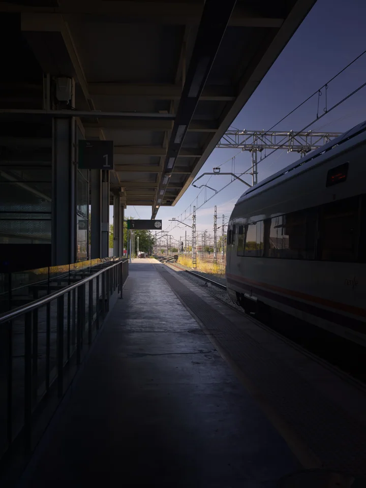 A train beside a quiet platform opening towards the light
