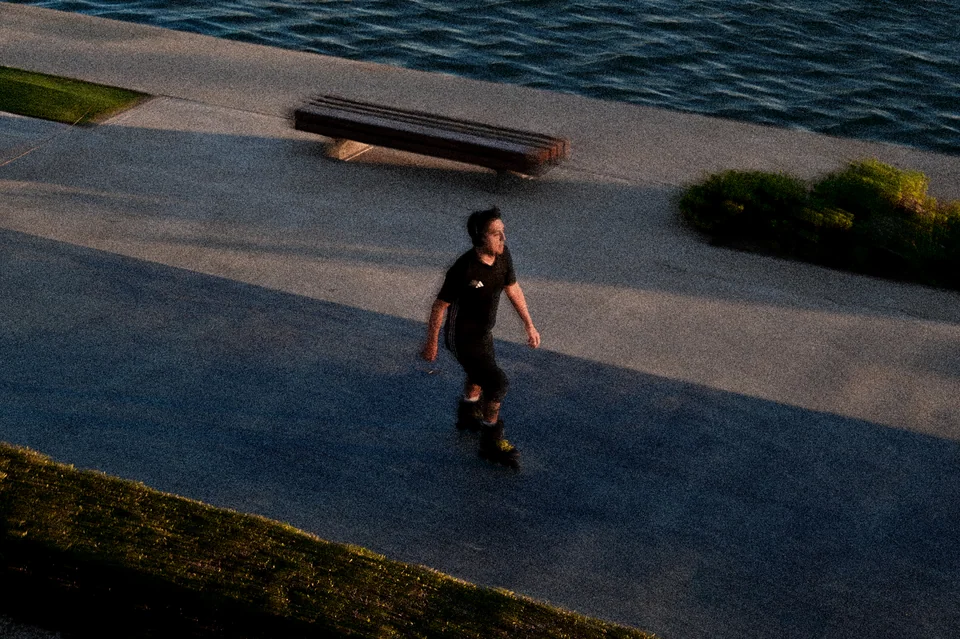 A runner passing through long shadows by the waterfront