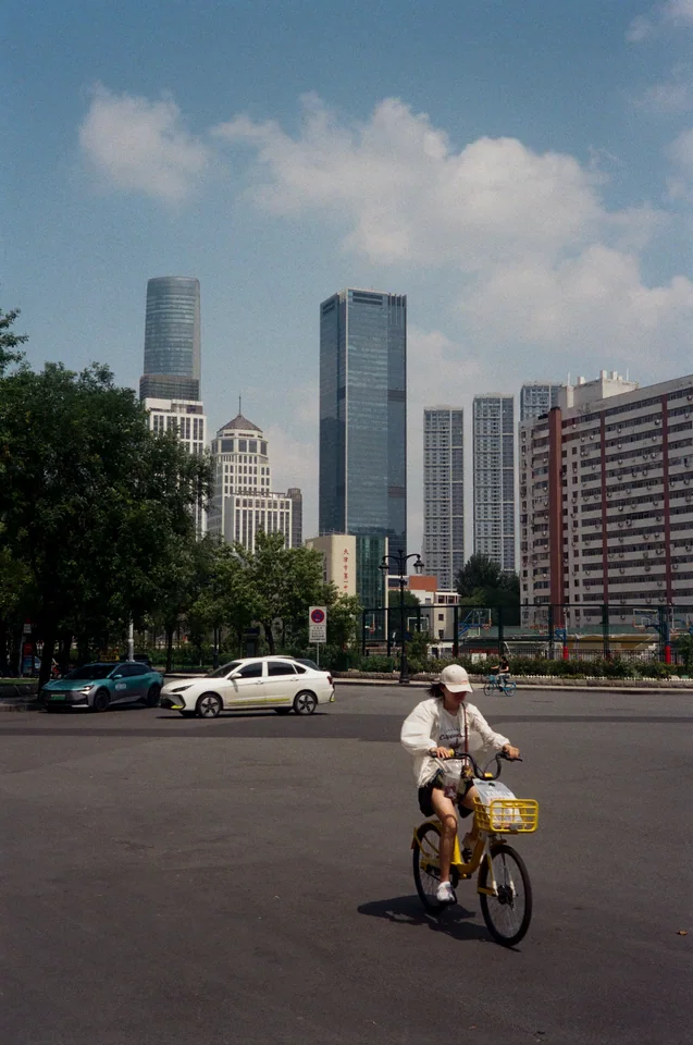 A cyclist passing through a sunlit city street